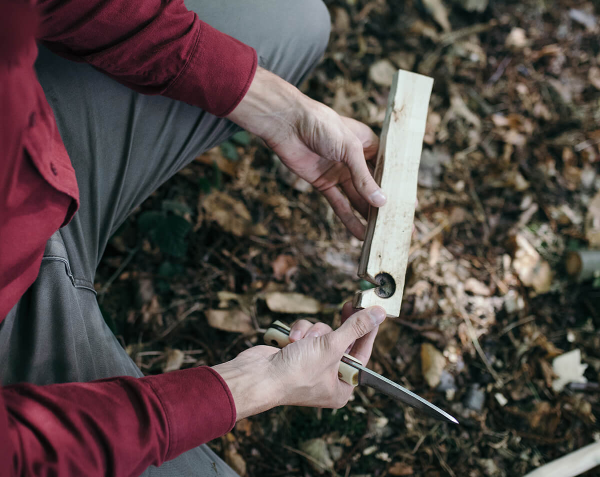 Dan Hume presents a split log with a notch cut in one edge, used as a hearth for fire making.